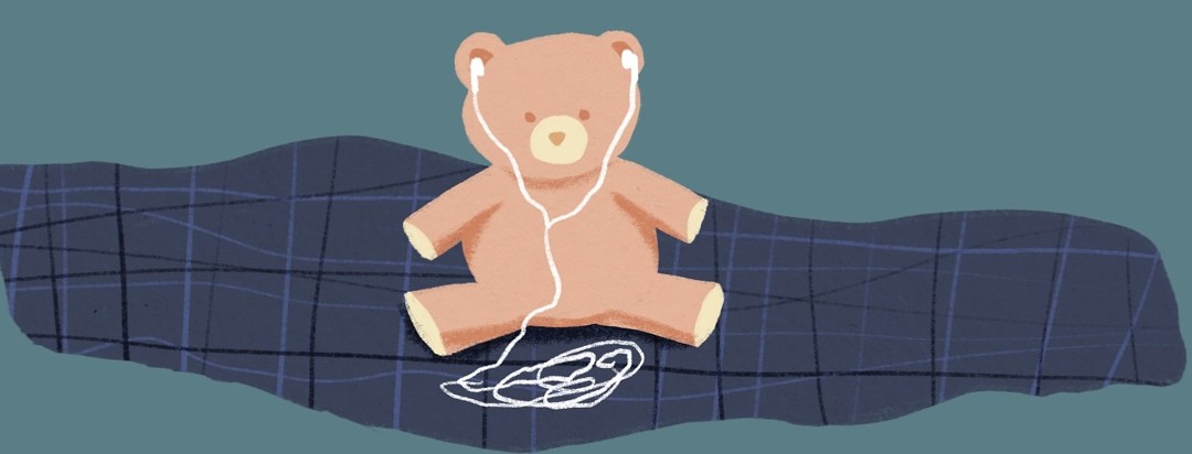a stuffed animal wearing earbuds and sitting on a blanket