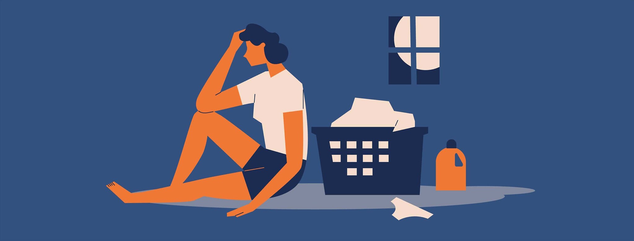 Tired woman sitting by a basket of dirty laundry at night