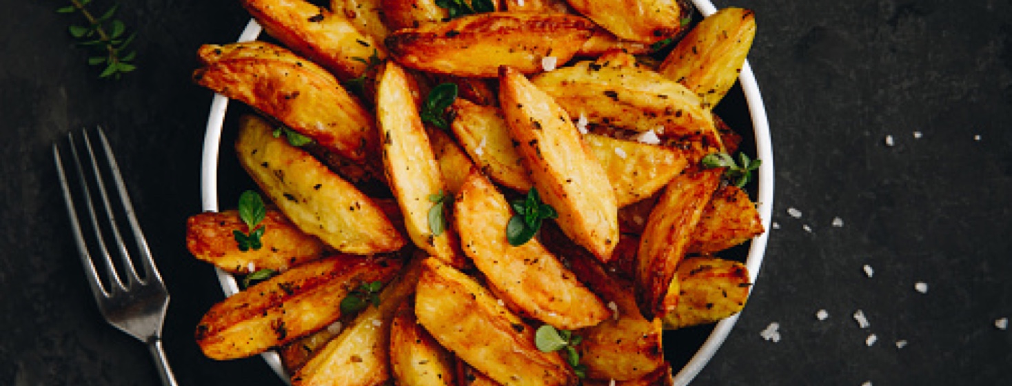 potato wedges in frying pan on dark stone background