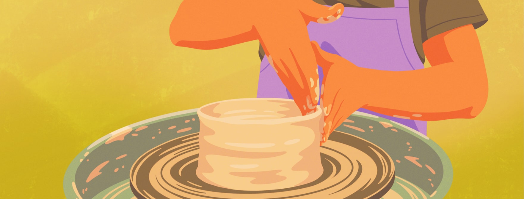 An individual wearing a purple apron leans over a pottery wheel molding clay.